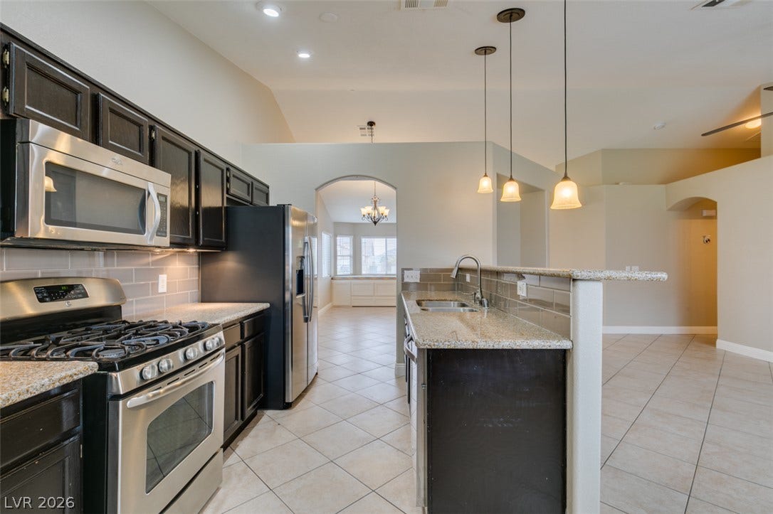 437 Waterwheel Falls Drive, Henderson, NV 89015 An open kitchen layout showcases high ceilings, granite countertops, and tile flooring throughout.