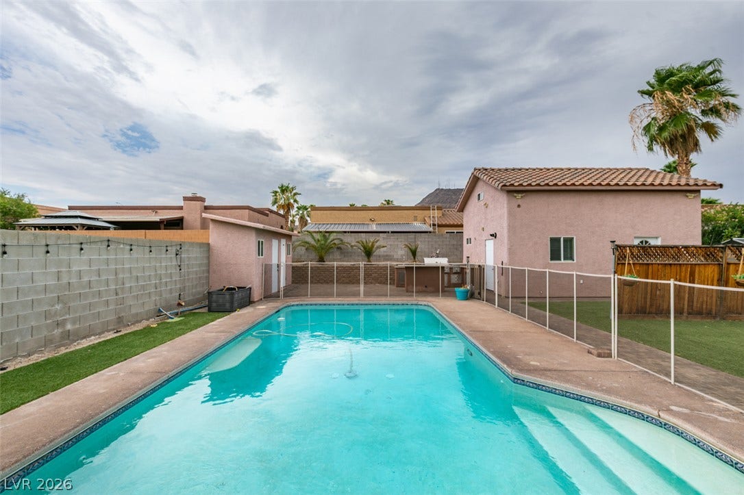 437 Waterwheel Falls Drive, Henderson, NV 89015 An inviting backyard features a sparkling blue swimming pool surrounded by clean concrete decking.