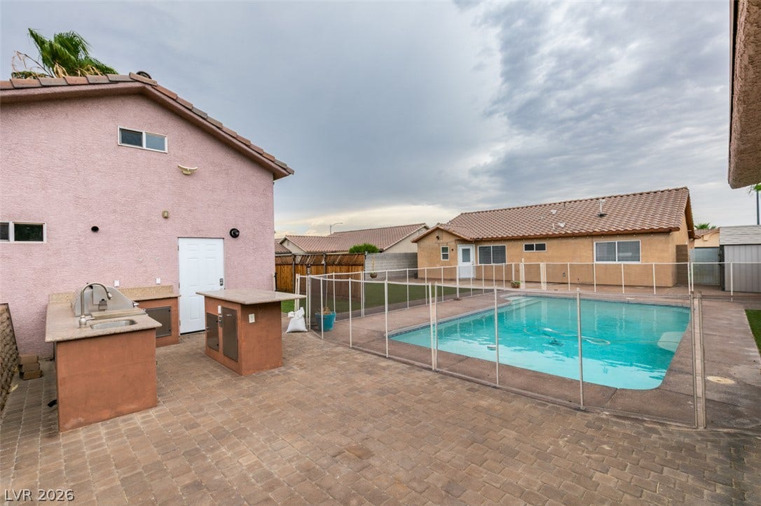 437 Waterwheel Falls Drive, Henderson, NV 89015 An inviting backyard features a paved patio, built-in outdoor kitchen, and fenced swimming pool.