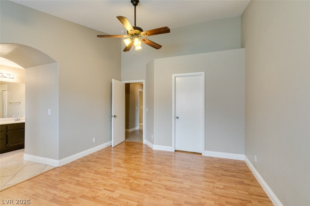 437 Waterwheel Falls Drive, Henderson, NV 89015 High vaulted ceilings and rich wood-styled flooring anchor this versatile secondary bedroom space.