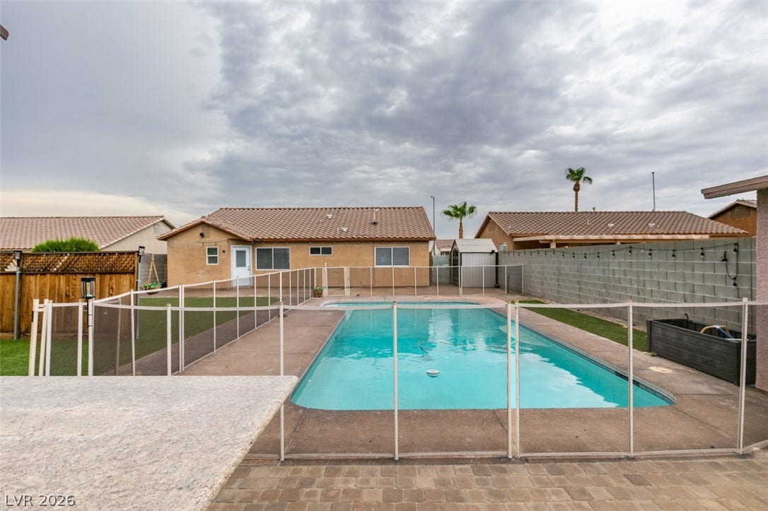 437 Waterwheel Falls Drive, Henderson, NV 89015 An inviting backyard oasis features a fenced sparkling pool set against a tile-roofed ranch home.