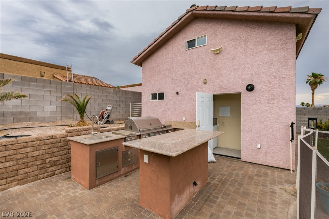 437 Waterwheel Falls Drive, Henderson, NV 89015 An outdoor kitchen with built-in grilling and prep areas sits on a paved backyard patio.