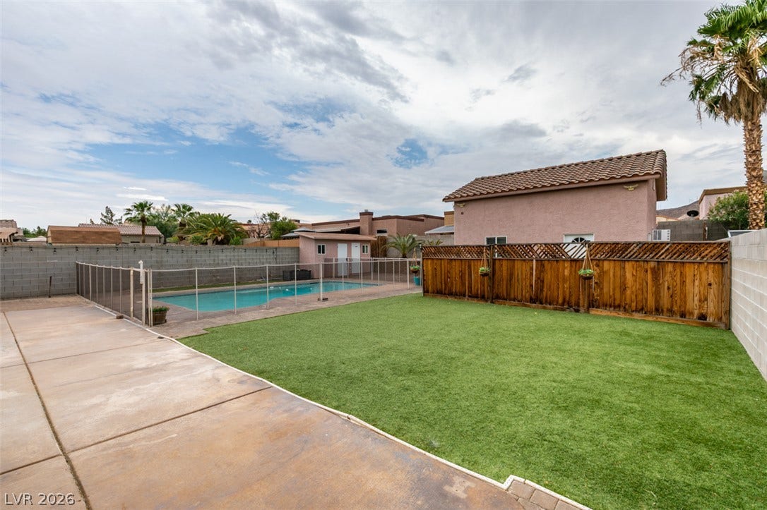 437 Waterwheel Falls Drive, Henderson, NV 89015 Concrete hardscaping leads to a manicured lawn area and a fenced-in swimming pool.