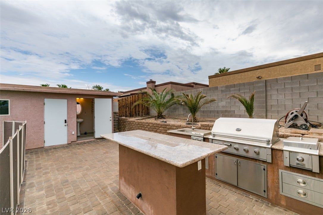 437 Waterwheel Falls Drive, Henderson, NV 89015 An outdoor kitchen features durable stone counters and built-in appliances over paver stone flooring.