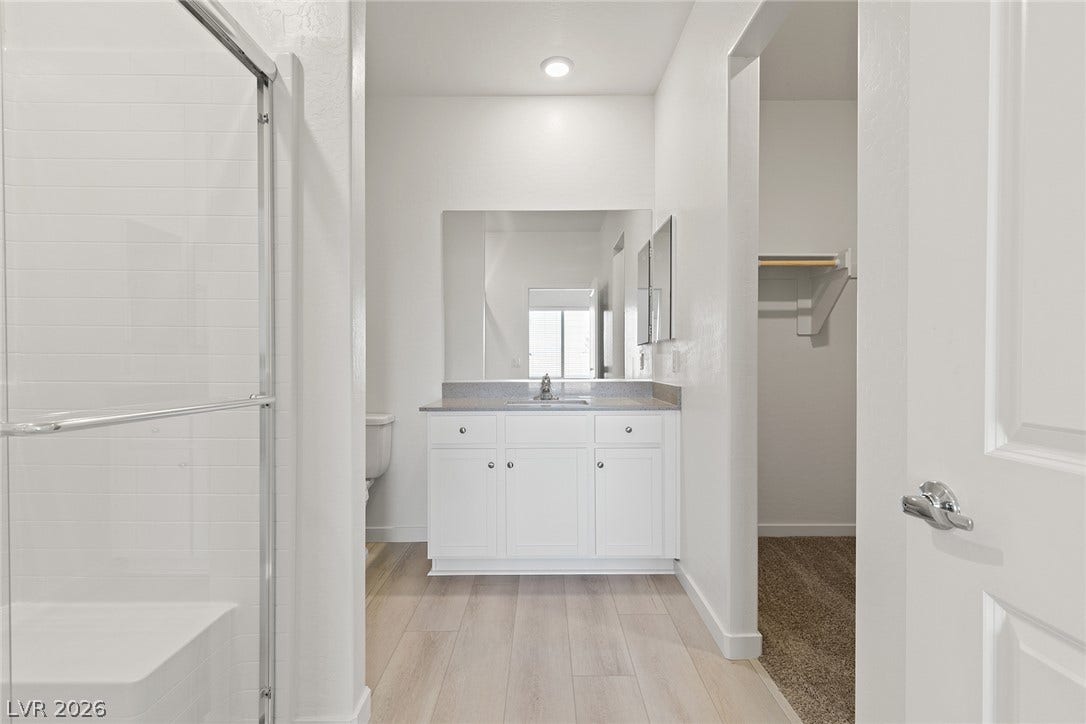 Tiled shower and a modern vanity lead directly into an adjacent walk-in closet.