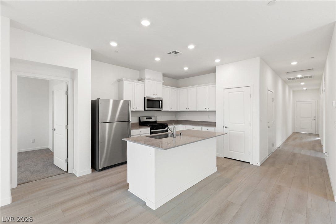 2754 Avril Point Street, Las Vegas, NV 89156 Recessed lighting illuminates wood-look flooring and a functional central island with stone counters.