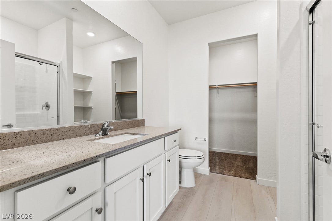 2754 Avril Point Street, Las Vegas, NV 89156 Modern stone counters and durable wood-look flooring anchor this pristine master bathroom design.
