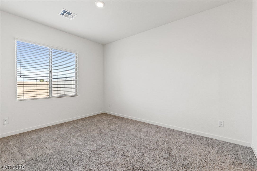 2754 Avril Point Street, Las Vegas, NV 89156 Plush carpeting and a large window frame this neutral, minimalist bedroom.