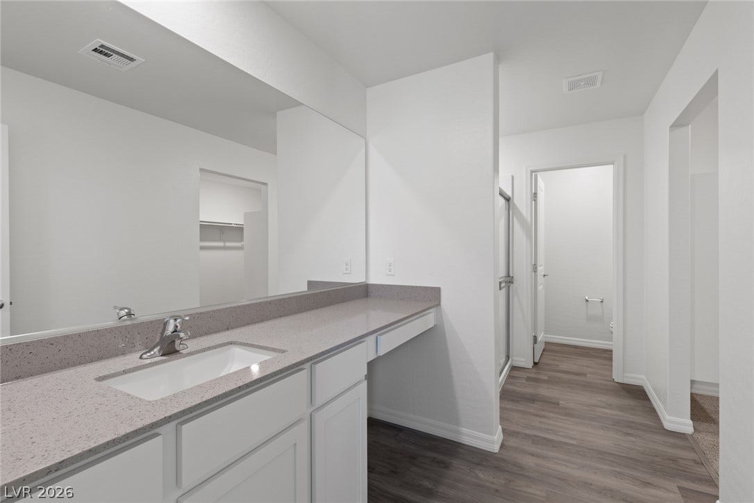 6740 Magnolia River Avenue, Las Vegas, NV 89156 Smooth stone countertops and streamlined cabinetry anchor this modern washroom design.