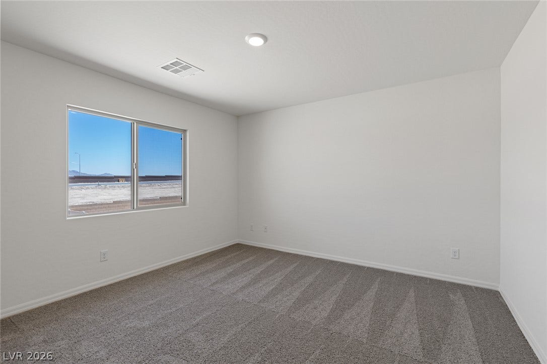 6740 Magnolia River Avenue, Las Vegas, NV 89156 Plush carpeting and a large window framing desert views define this versatile bedroom.