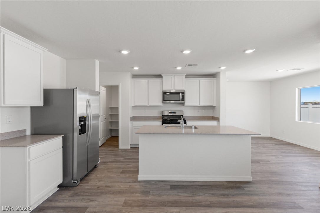 6740 Magnolia River Avenue, Las Vegas, NV 89156 Recessed lighting and warm wood-look flooring enhance this open-concept culinary space.