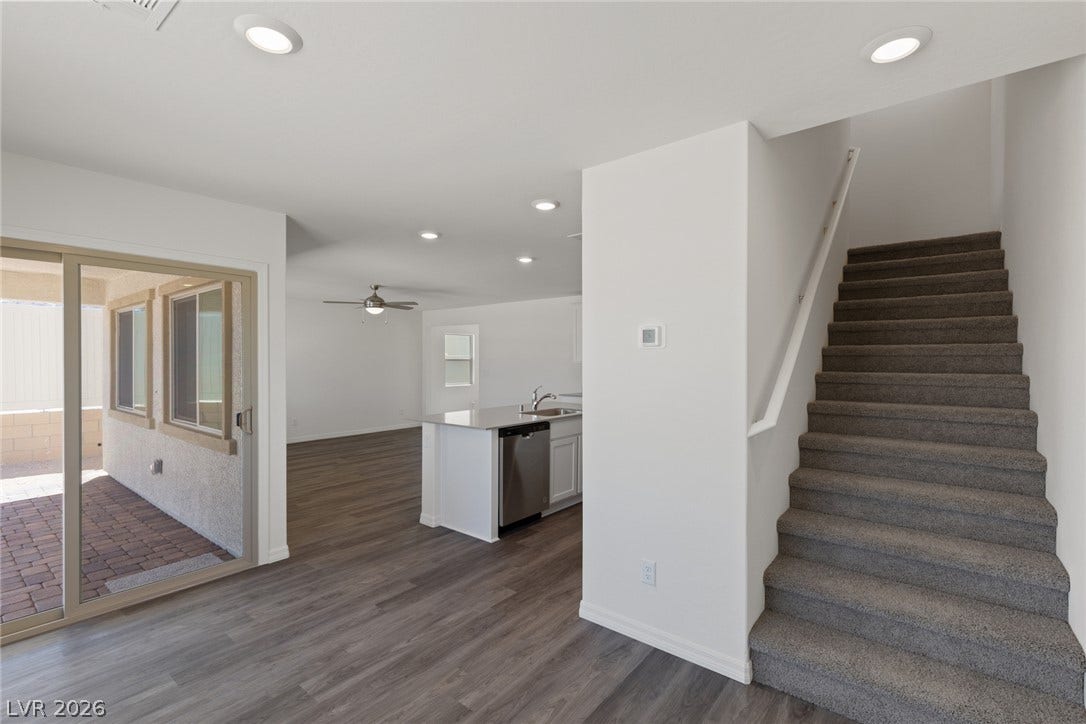 6740 Magnolia River Avenue, Las Vegas, NV 89156 An open floor plan connects the main living areas beside a carpeted staircase.