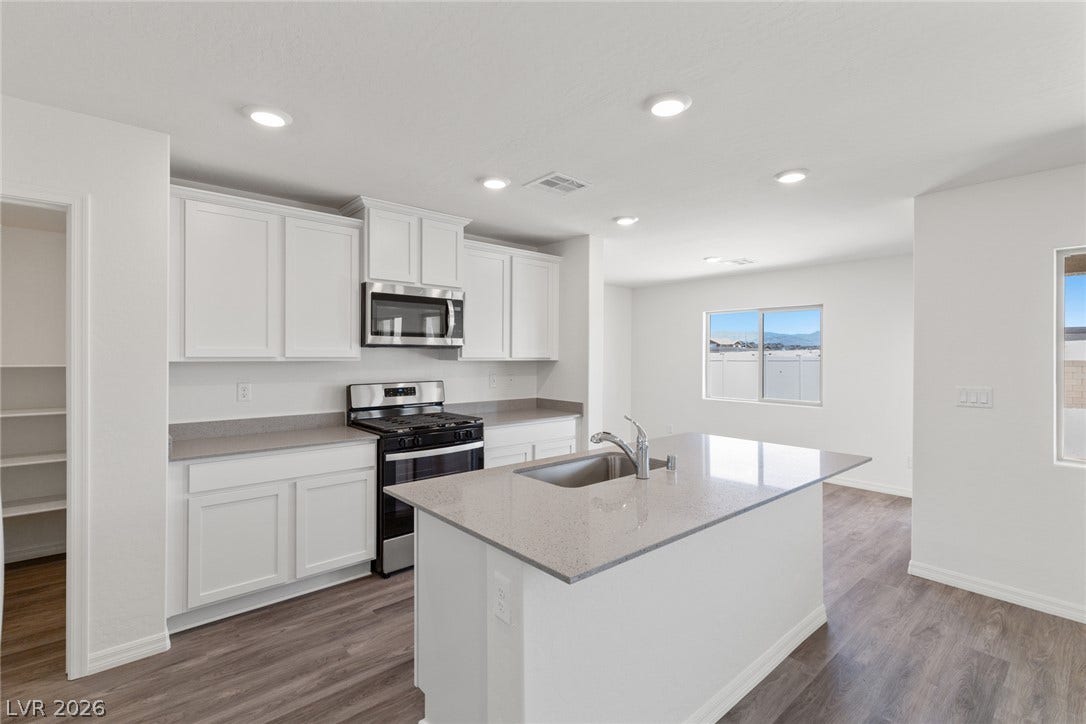 6740 Magnolia River Avenue, Las Vegas, NV 89156 Recessed lighting illuminates clean countertops and a central island in this open culinary space.
