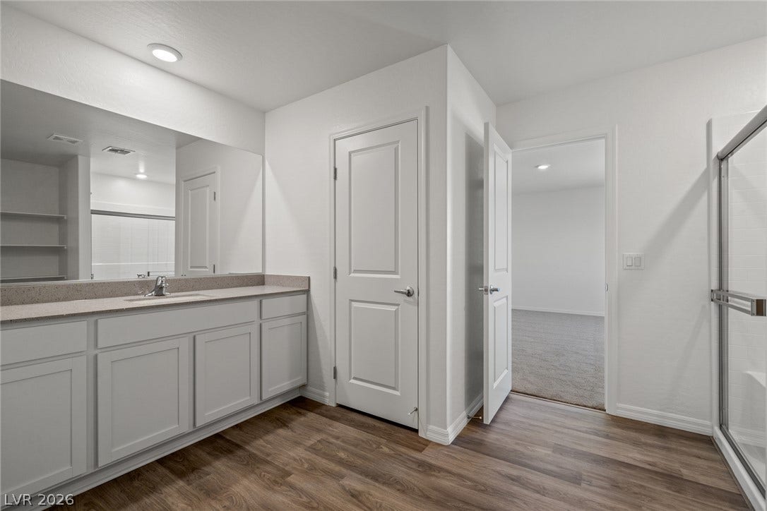 Streamlined cabinetry and wood-look flooring define this clean, modern bathroom layout.
