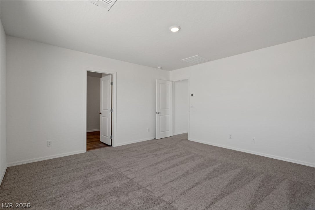 Soft plush carpeting anchors this versatile room under a smooth ceiling with integrated lighting.