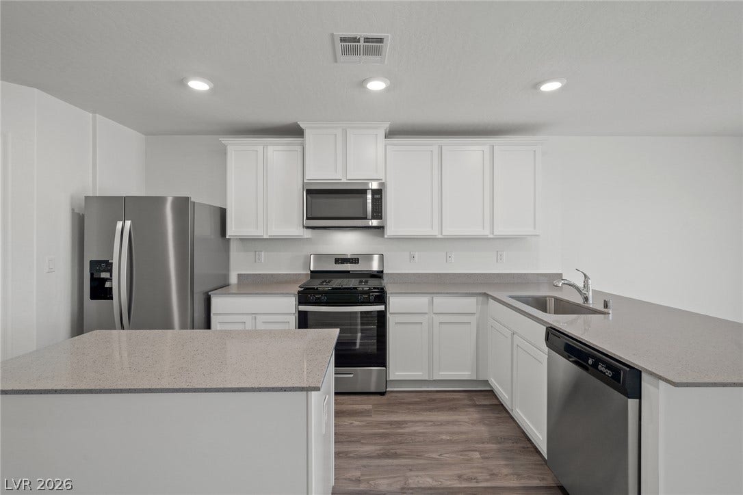 Streamlined cabinetry and clean countertops define this modern kitchen layout with wood-style flooring.