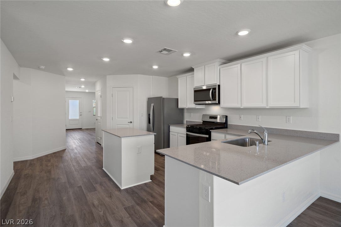 Polished stone countertops pair with clean cabinetry in this open kitchen layout.