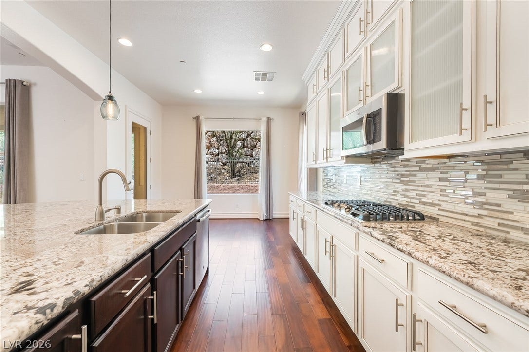 72 Rezzonico Drive, Henderson, NV 89011 Rich hardwood floors contrast with bright cabinetry and premium stone countertops in this modern kitchen.