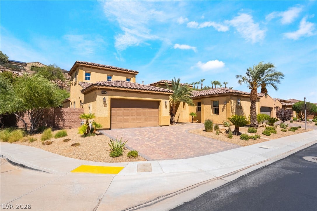 72 Rezzonico Drive, Henderson, NV 89011 Spanish tile roofs and warm stucco walls define this desert-landscaped home exterior.