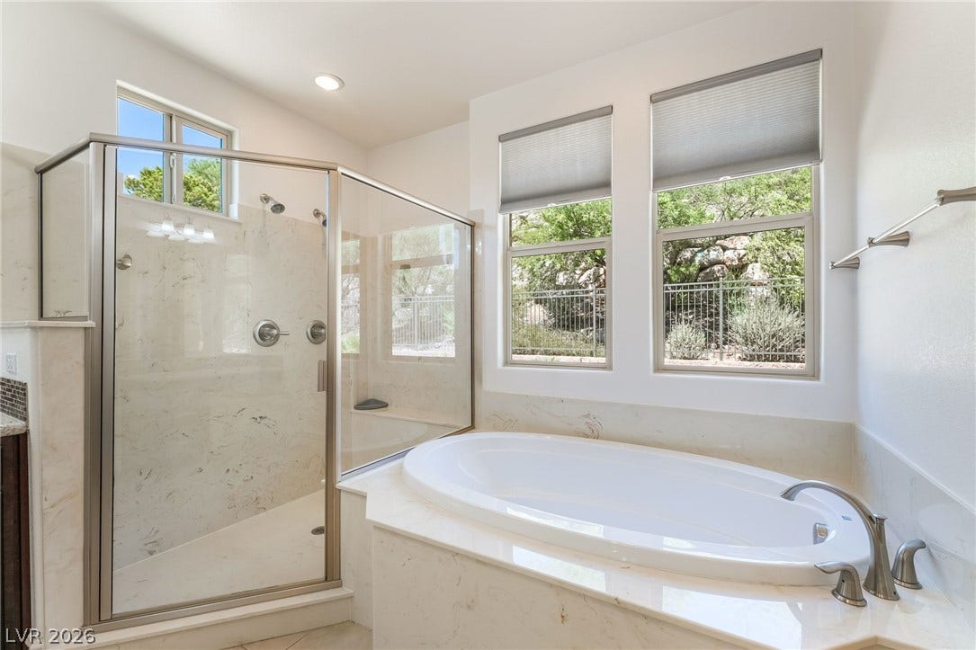 72 Rezzonico Drive, Henderson, NV 89011 A glass-enclosed shower and matching soaking tub coordinate beneath bright windows.