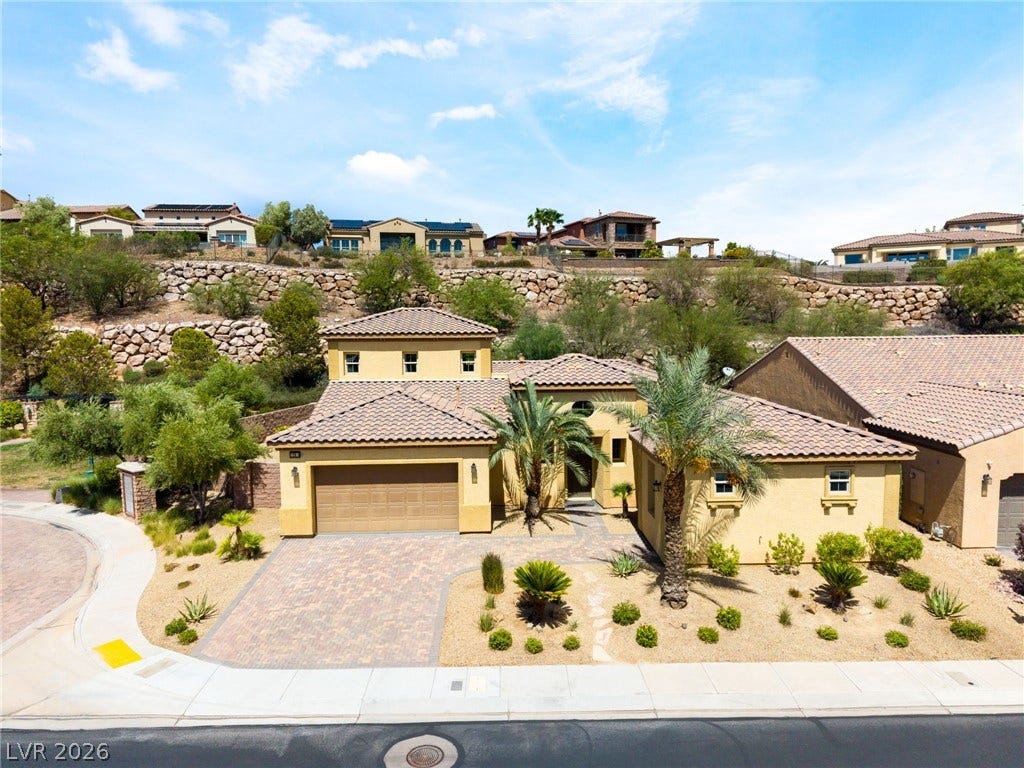 72 Rezzonico Drive, Henderson, NV 89011 Desert landscaping and a paved driveway complement this multi-level stucco home with tile roofing.