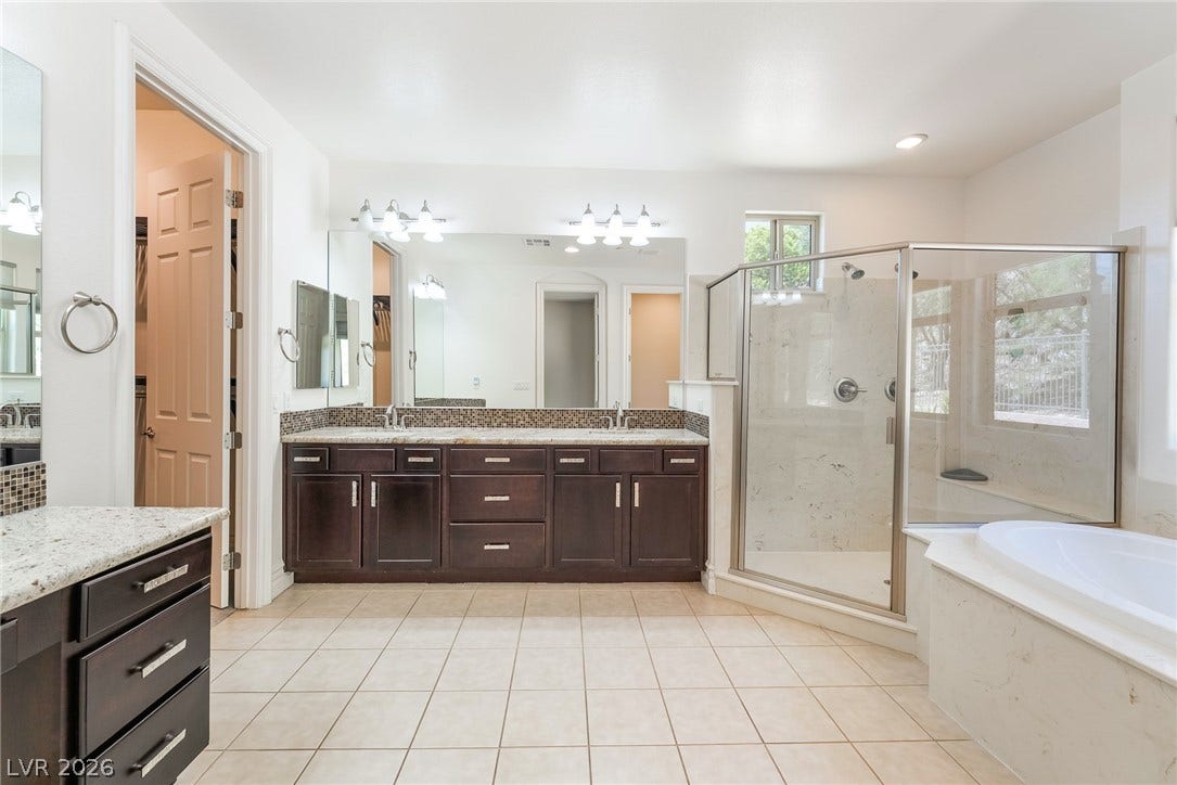 72 Rezzonico Drive, Henderson, NV 89011 Tiled flooring pairs with a double vanity, a glass shower, and a built-in tub.