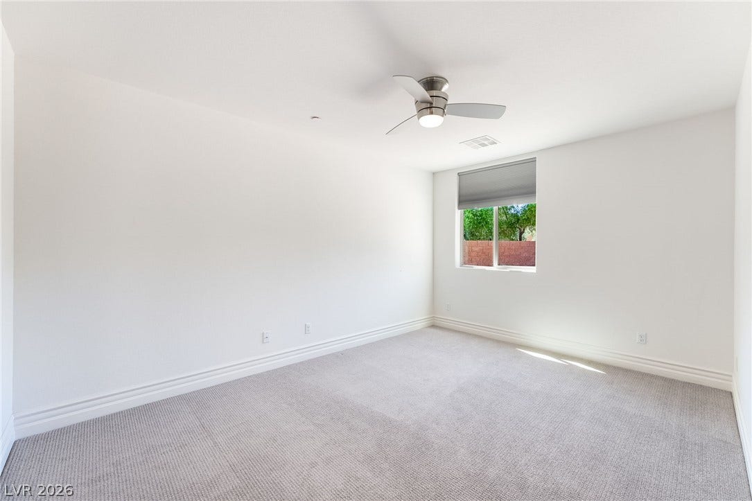 72 Rezzonico Drive, Henderson, NV 89011 Plush carpeting and baseboard molding frame this serene, minimalist bedroom space.