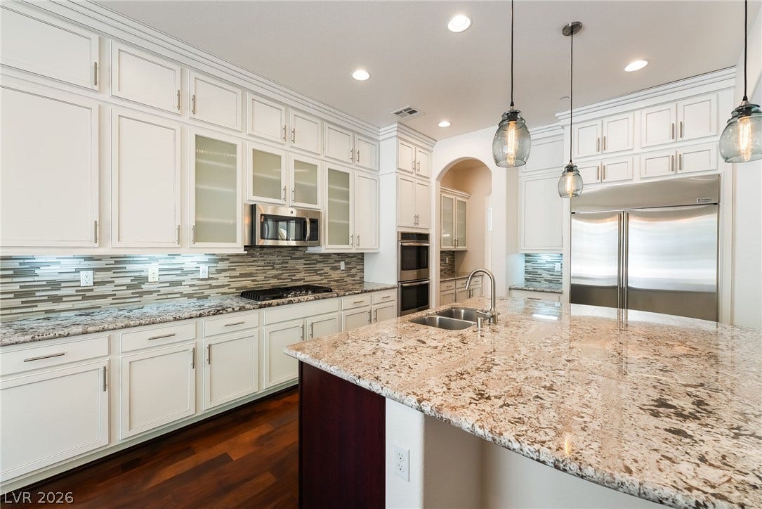72 Rezzonico Drive, Henderson, NV 89011 Rich hardwood floors complement the expansive granite countertops and elegant cabinetry in this culinary space.