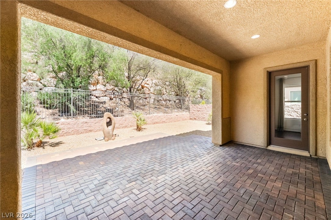 72 Rezzonico Drive, Henderson, NV 89011 A sheltered paver patio looks out over a private, fenced yard against a natural hillside.