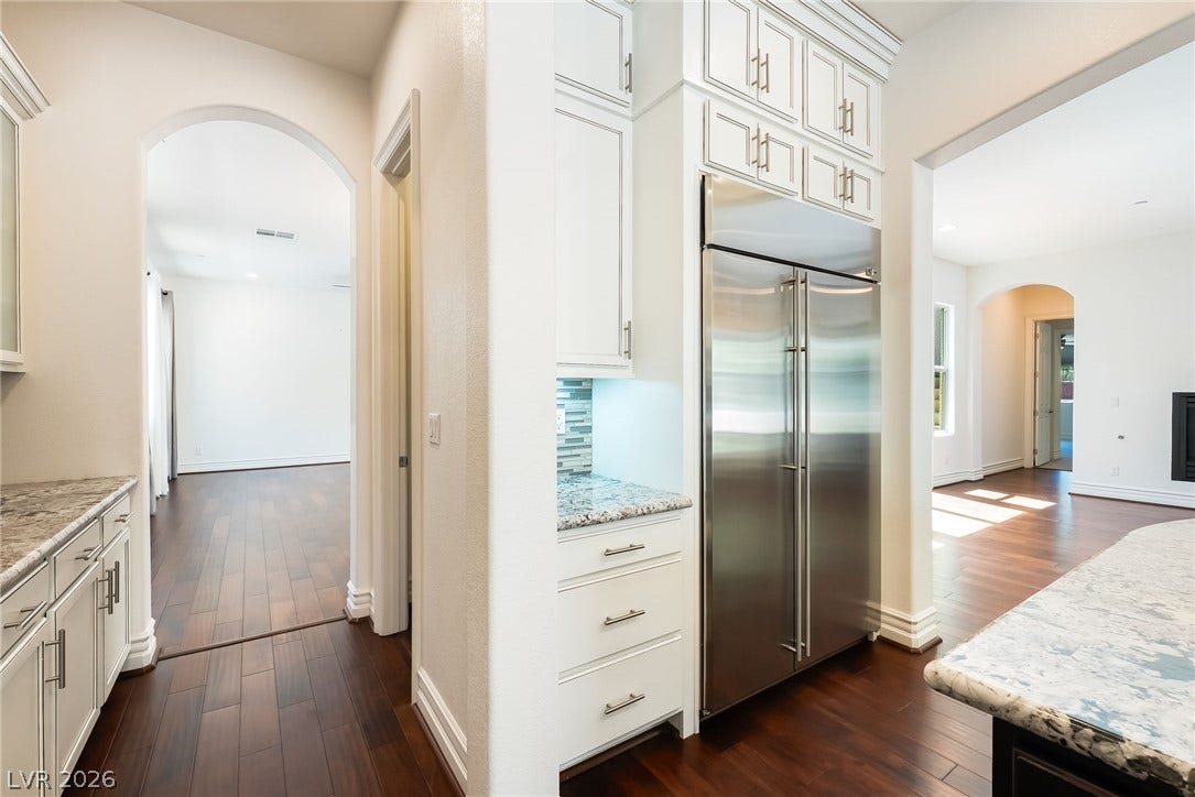 72 Rezzonico Drive, Henderson, NV 89011 Gleaming hardwood floors and classic arched doorways connect the elegant kitchen to adjacent living spaces.