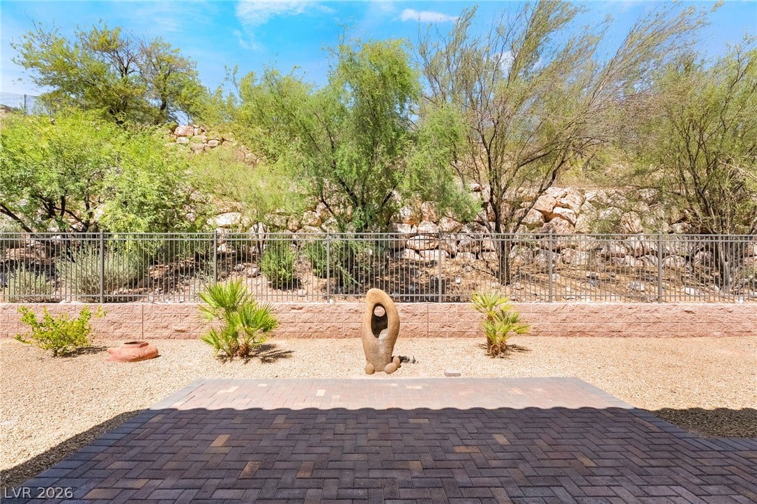 72 Rezzonico Drive, Henderson, NV 89011 Paver patio borders a gravel yard set against a natural rocky hillside backdrop.