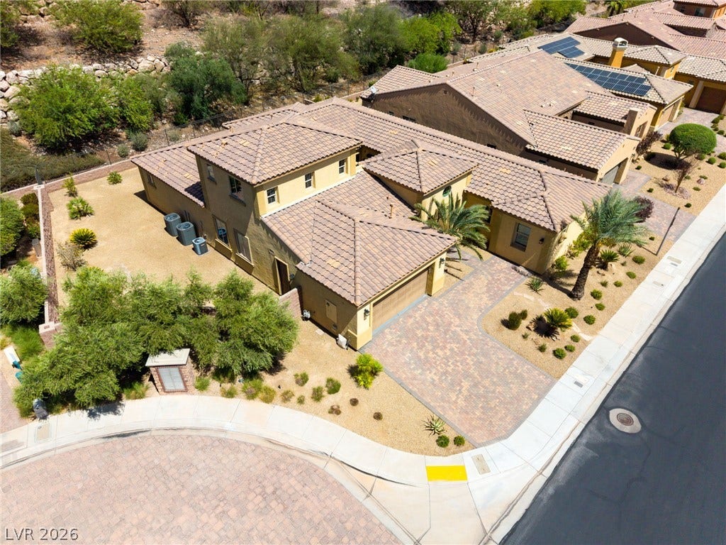 72 Rezzonico Drive, Henderson, NV 89011 An aerial perspective showcases the tiled rooflines, paved driveway, and desert landscaping of this home.
