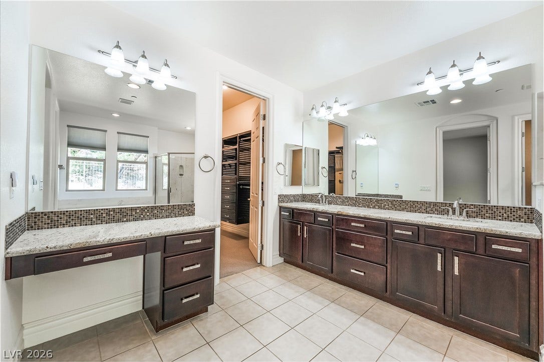 72 Rezzonico Drive, Henderson, NV 89011 Rich wood cabinetry and stone countertops elevate this spacious bathroom with an integrated makeup vanity.