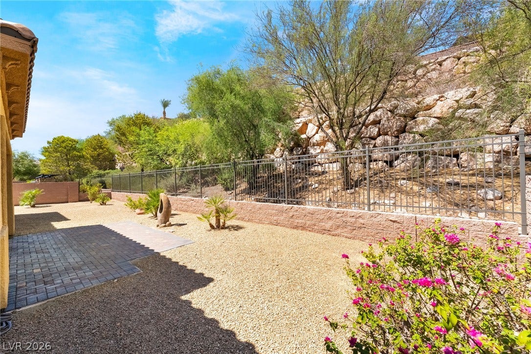 72 Rezzonico Drive, Henderson, NV 89011 Low-maintenance desert landscaping and a paved patio area sit bordered by a secure perimeter fence.