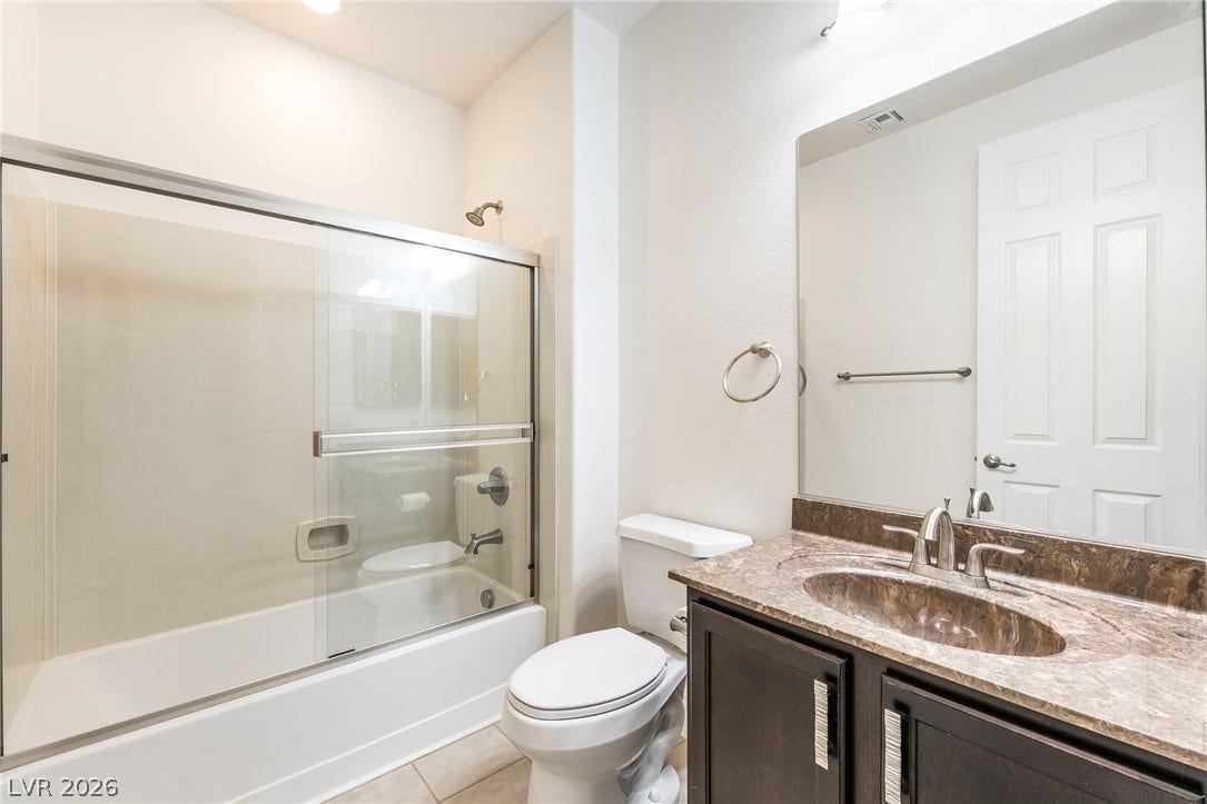 72 Rezzonico Drive, Henderson, NV 89011 Polished stone counters and a sleek glass shower enclosure elevate this functional bathroom.