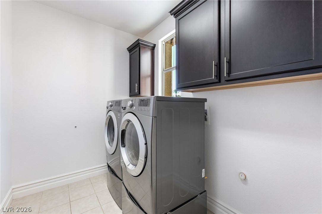 72 Rezzonico Drive, Henderson, NV 89011 A functional laundry area with ceramic tile flooring and dark cabinetry.