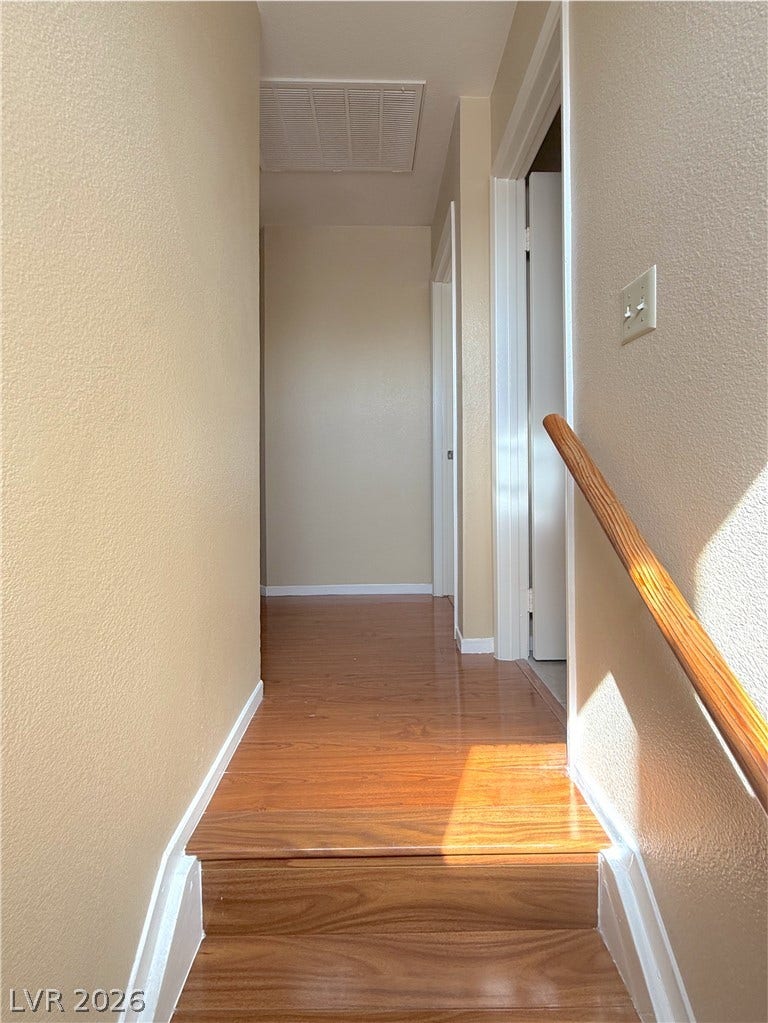 601 Avon Avenue, Henderson, NV 89014 Gleaming wood-look floors line this upper level hallway connected by a wooden handrail.