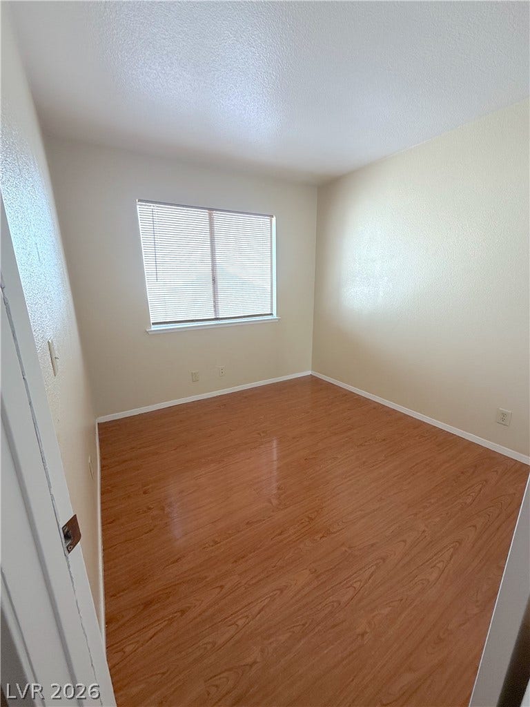 601 Avon Avenue, Henderson, NV 89014 Rich wood flooring anchors this versatile bedroom featuring a wide window.