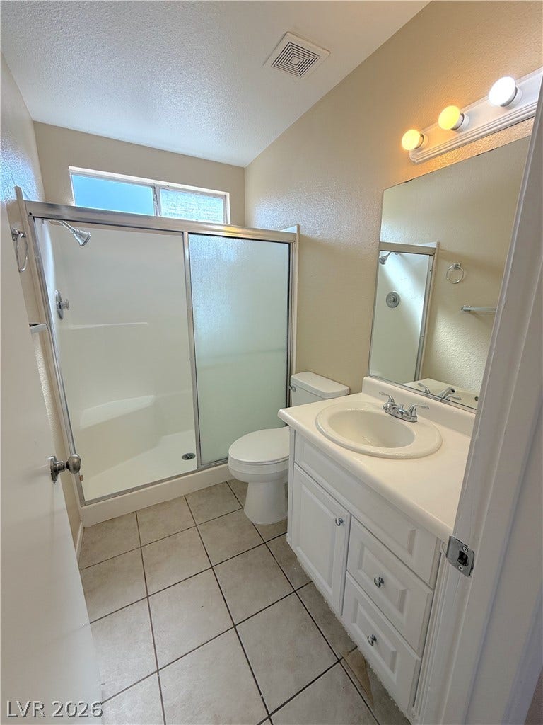 601 Avon Avenue, Henderson, NV 89014 Tiled flooring and a walk-in shower with sliding glass doors highlight this bathroom.