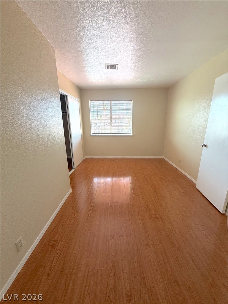 601 Avon Avenue, Henderson, NV 89014 Polished wood-style flooring and a large window define this versatile secondary bedroom.