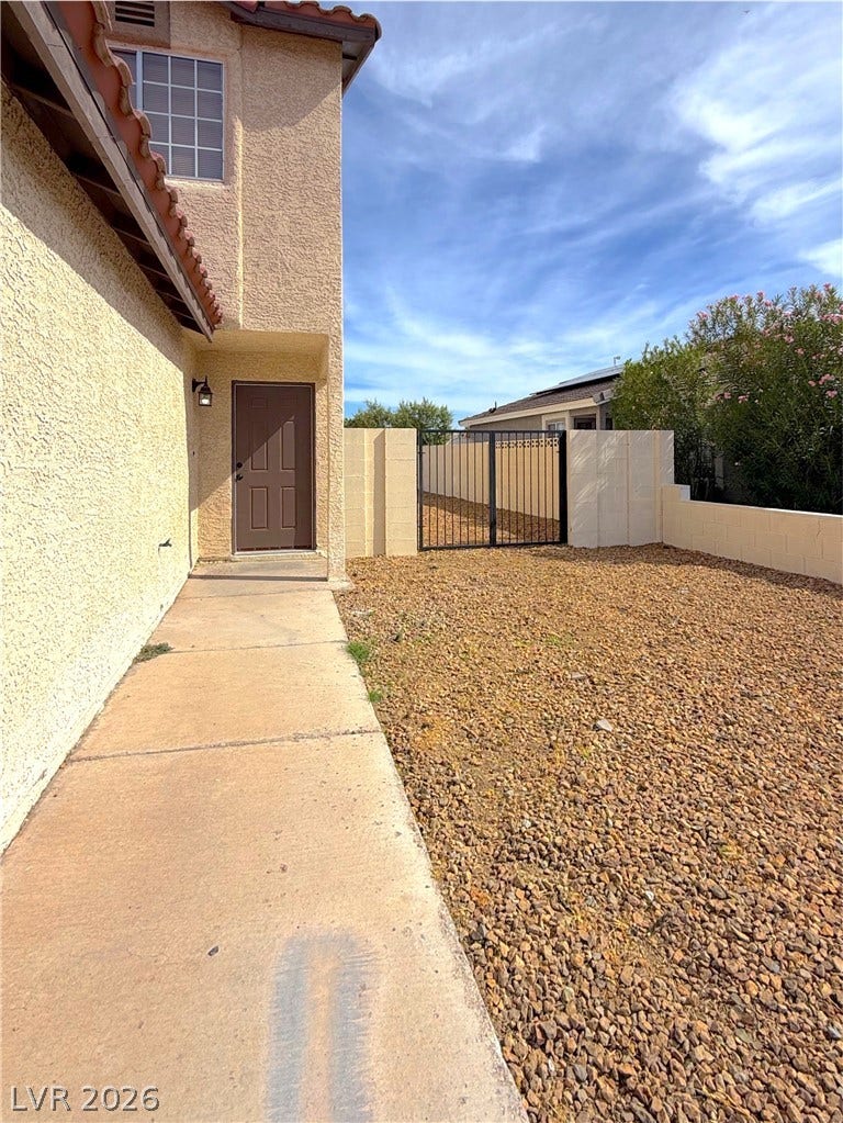 601 Avon Avenue, Henderson, NV 89014 Concrete pathways wind through low-maintenance desert landscaping alongside a textured stucco exterior.