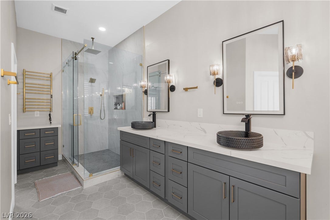 8848 Rainbow Ridge Drive, Las Vegas, NV 89117 A spacious double vanity and a glass-enclosed shower highlight this modern bathroom.
