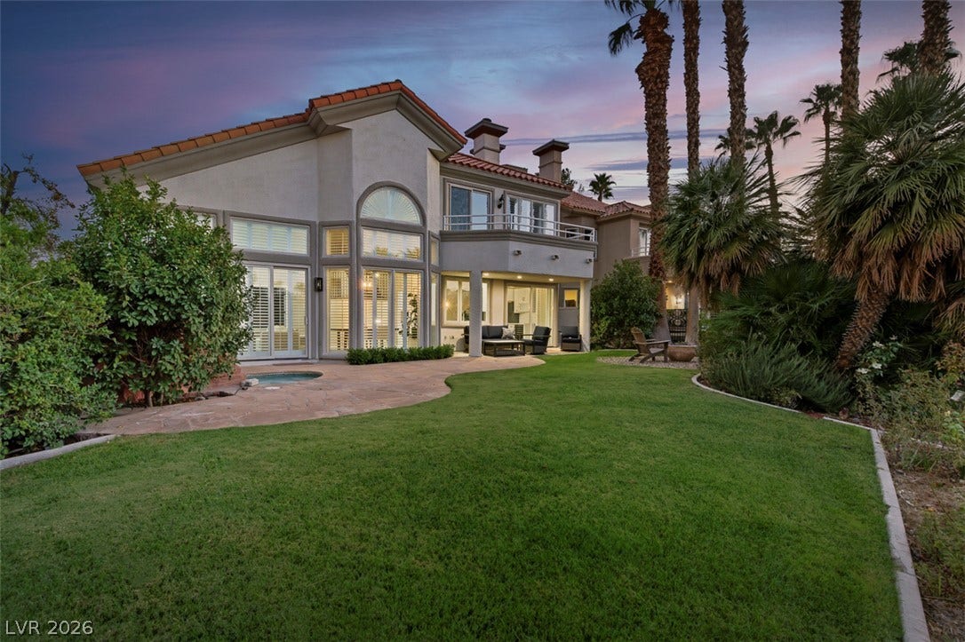 8848 Rainbow Ridge Drive, Las Vegas, NV 89117 Manicured lawns and swaying palm trees frame this elegant multi-level home under a twilight sky.