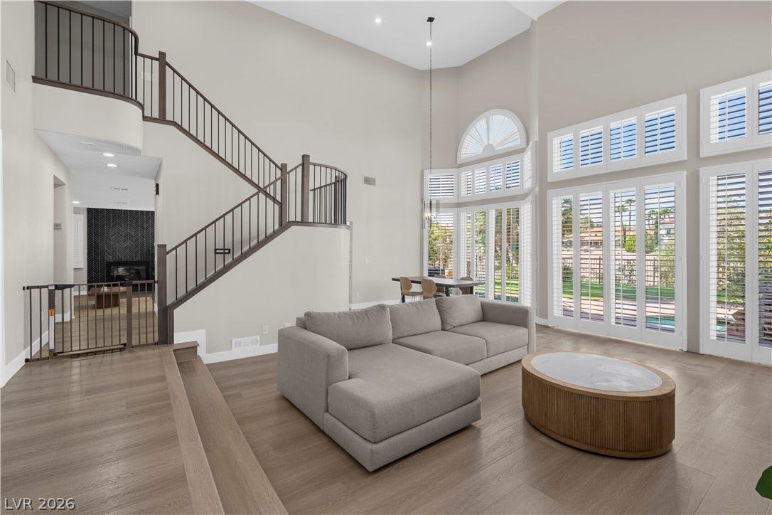 8848 Rainbow Ridge Drive, Las Vegas, NV 89117 Sunlight streams through towering plantation shutters into a grand living space with hardwood flooring.