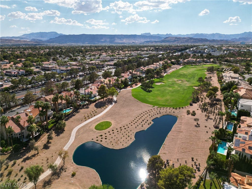 8848 Rainbow Ridge Drive, Las Vegas, NV 89117 A green golf course with a quiet pond nestles against a backdrop of distant mountains.