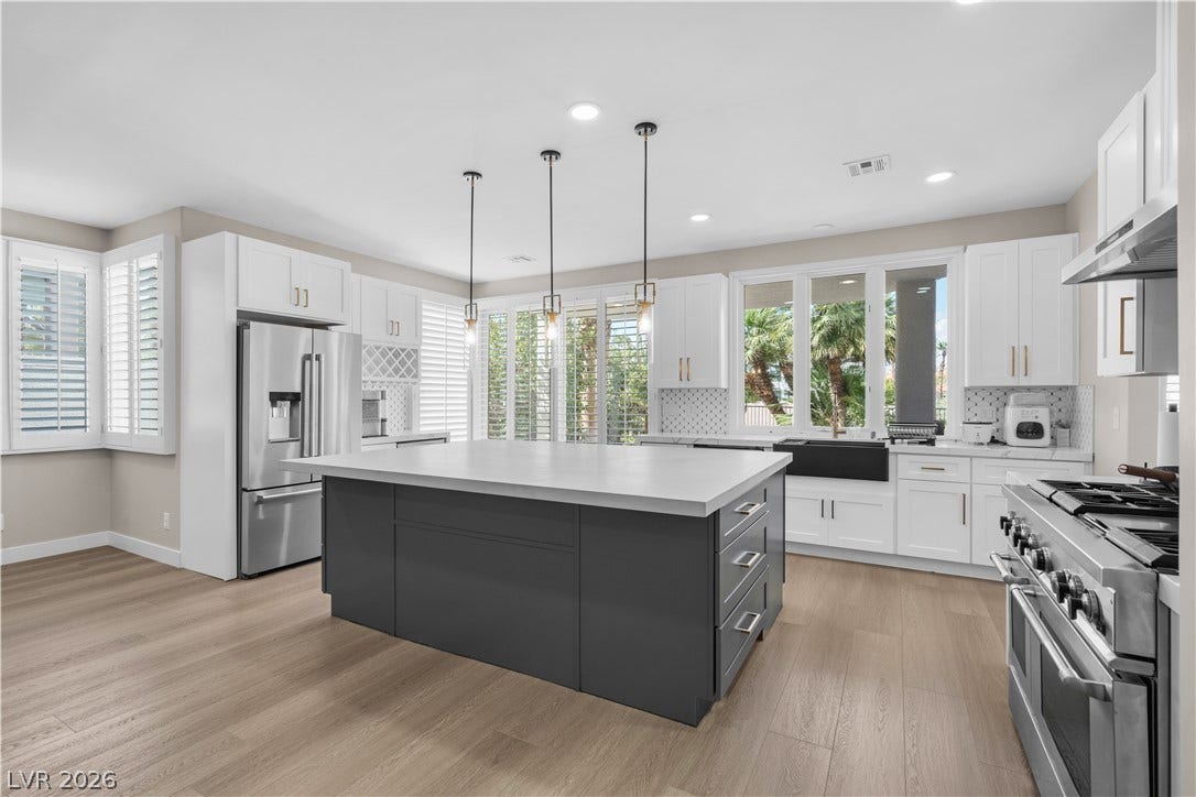 8848 Rainbow Ridge Drive, Las Vegas, NV 89117 An expansive central island grounds this contemporary culinary space flanked by light wood-toned flooring.