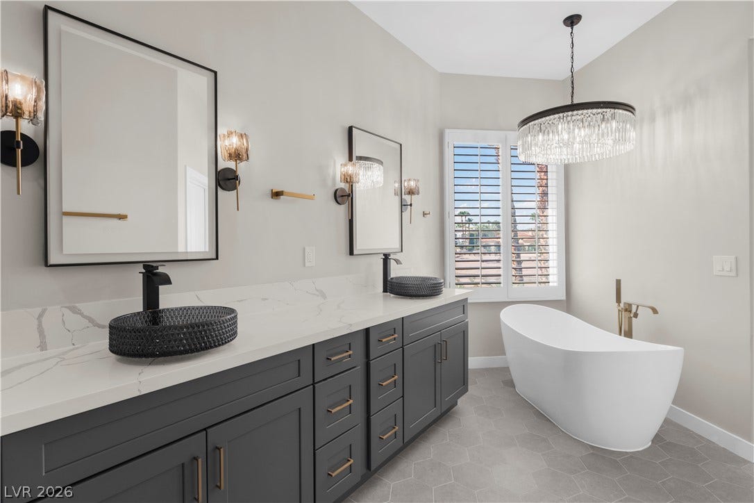 8848 Rainbow Ridge Drive, Las Vegas, NV 89117 A freestanding tub and sleek double vanity define this elegant primary bathroom.