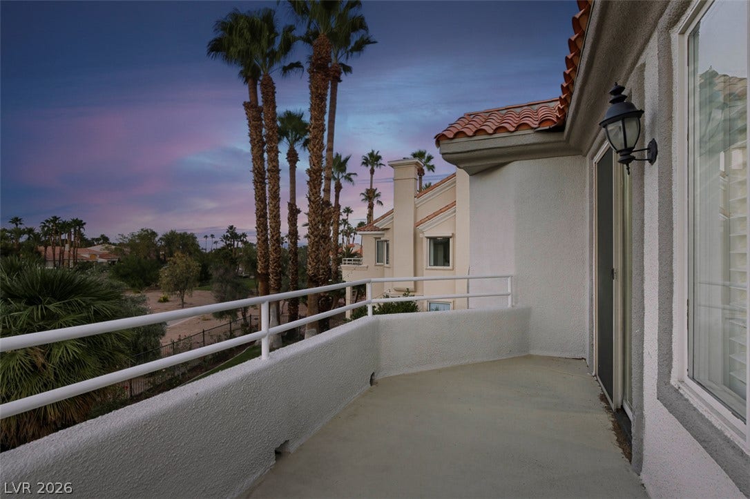 8848 Rainbow Ridge Drive, Las Vegas, NV 89117 Palm trees and sunset views frame this concrete balcony with classic Spanish tile roof details.
