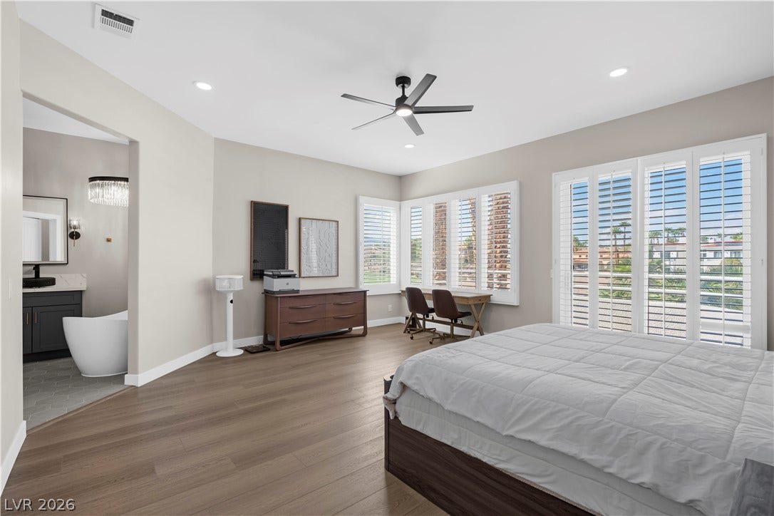 8848 Rainbow Ridge Drive, Las Vegas, NV 89117 A spacious bedroom offers warm wood floors, plantation shutters, and access to an adjoining bathroom.