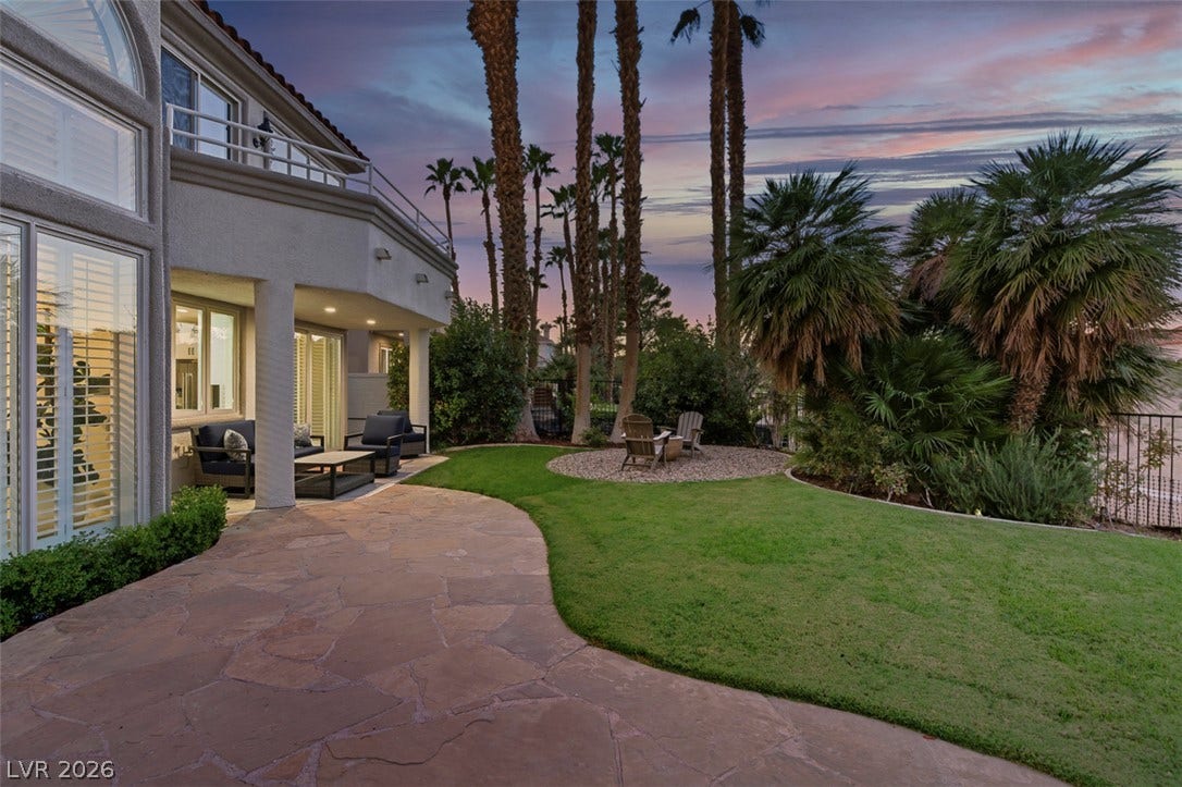 8848 Rainbow Ridge Drive, Las Vegas, NV 89117 Manicured lawns and stone pathways wind through a lush backyard framed by towering palm trees.
